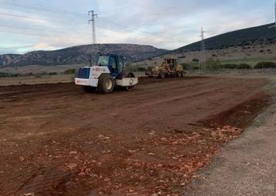 Rodillo compactador y motoniveladora nivelando una explanada