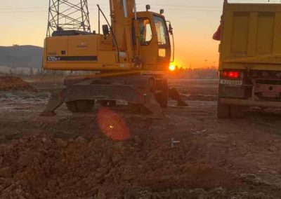 Excavadora trabajando al amanecer junto a una línea eléctrica